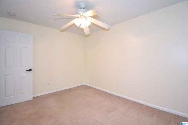 spare room featuring light colored carpet, ceiling fan, and baseboards