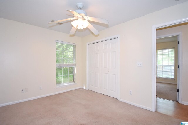 unfurnished bedroom with light carpet, multiple windows, a closet, and baseboards