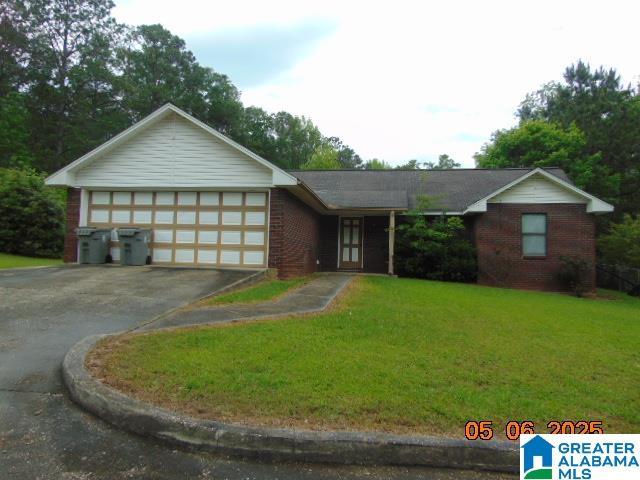 ranch-style home with brick siding, aphalt driveway, a front lawn, and an attached garage