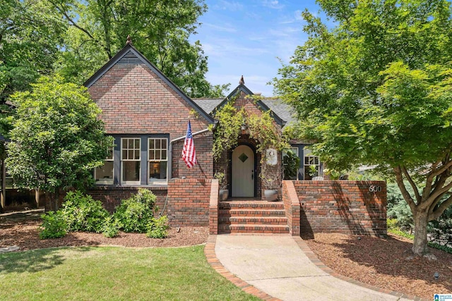 tudor house with brick siding and a front yard