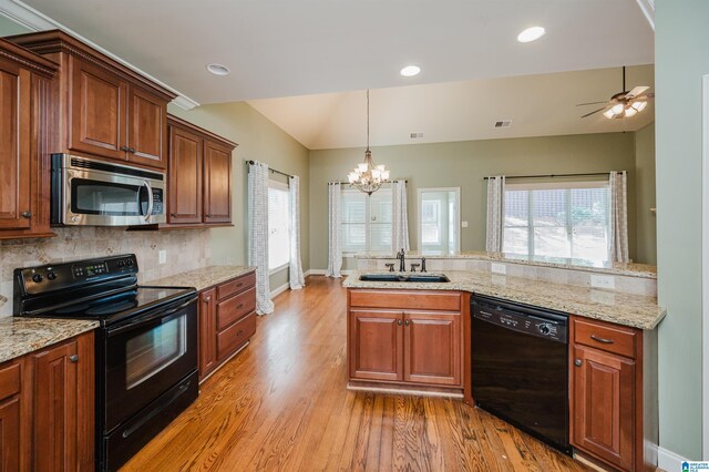 kitchen featuring black appliances, a sink, a chandelier, baseboards, and light wood-style floors