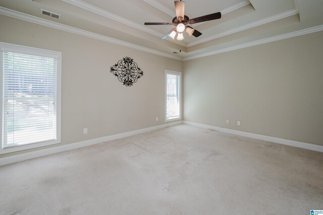 unfurnished room featuring a tray ceiling, ornamental molding, a ceiling fan, light colored carpet, and baseboards