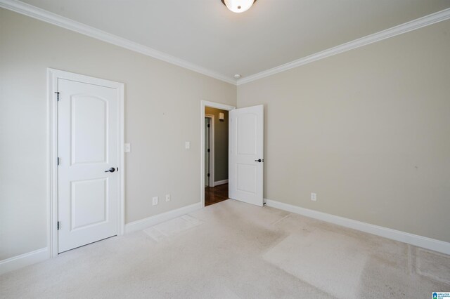 unfurnished bedroom with crown molding, carpet floors, and baseboards