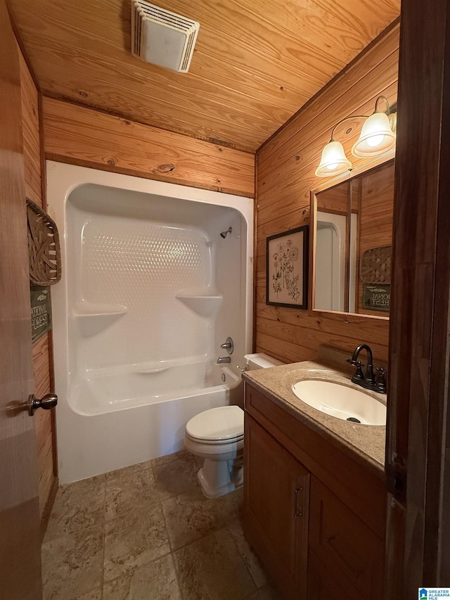 full bathroom with wood walls, toilet, vanity, shower / bathtub combination, and stone finish floors