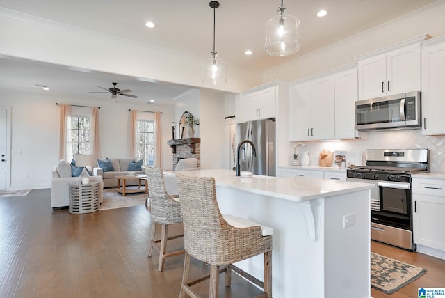 0571 Preserve Pkwy, Hoover, AL 35226 - kitchen with stainless steel appliances, a breakfast bar area, an island with sink, white cabinetry, and decorative light fixtures