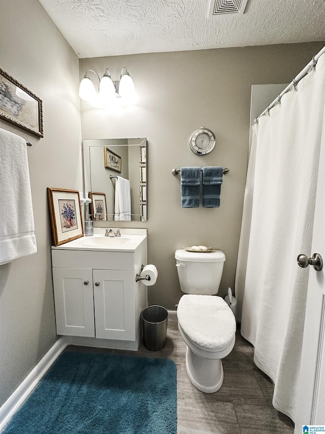 bathroom featuring vanity, wood finished floors, toilet, a textured ceiling, and baseboards