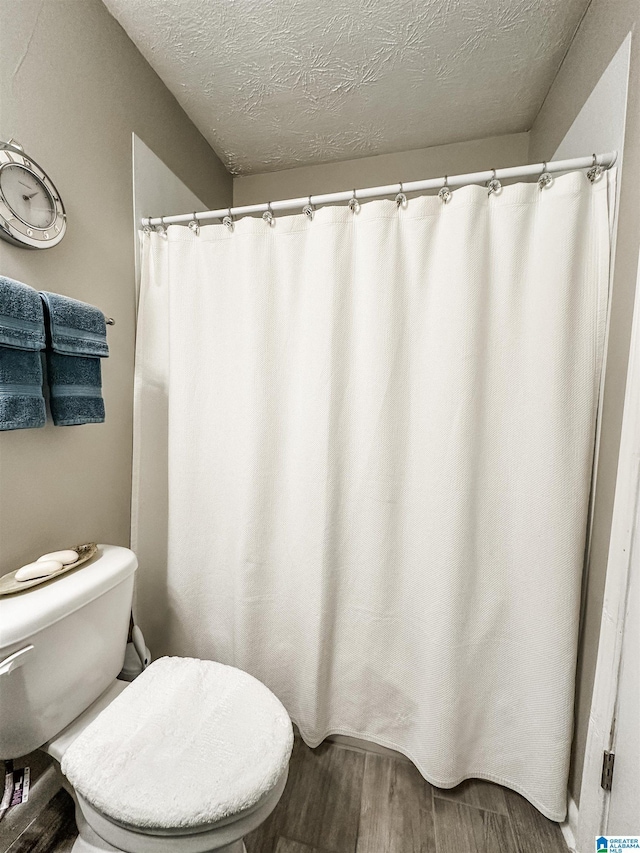 bathroom featuring wood finished floors, toilet, and a textured ceiling