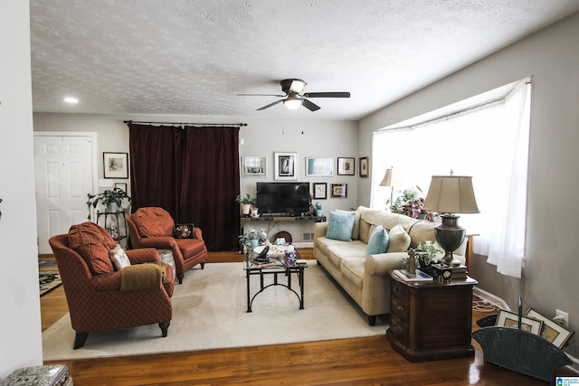 living area with plenty of natural light, a ceiling fan, wood finished floors, and a textured ceiling