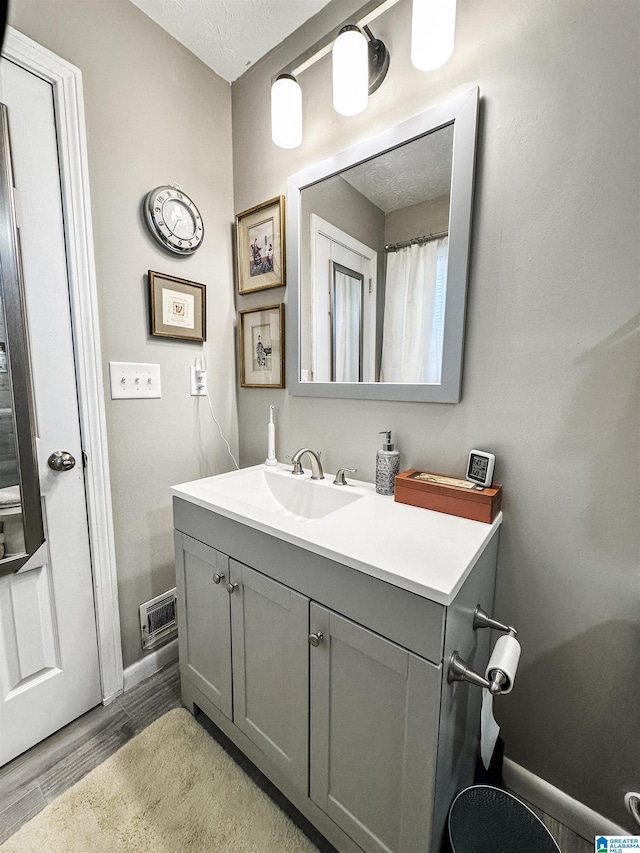 bathroom featuring vanity, baseboards, and wood finished floors