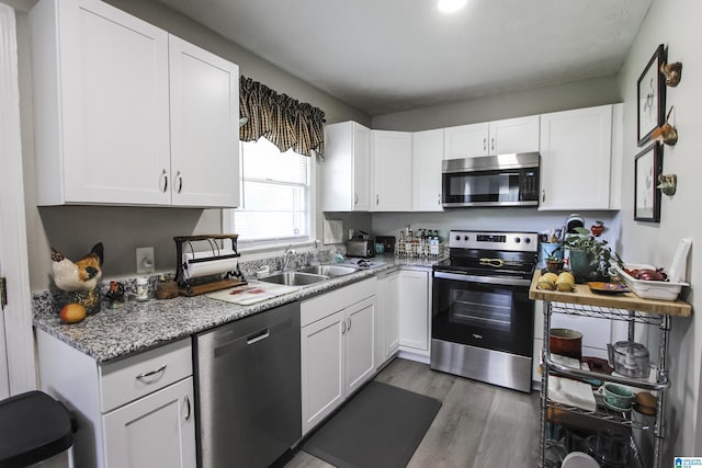 kitchen featuring stainless steel appliances, a sink, white cabinets, and light wood finished floors