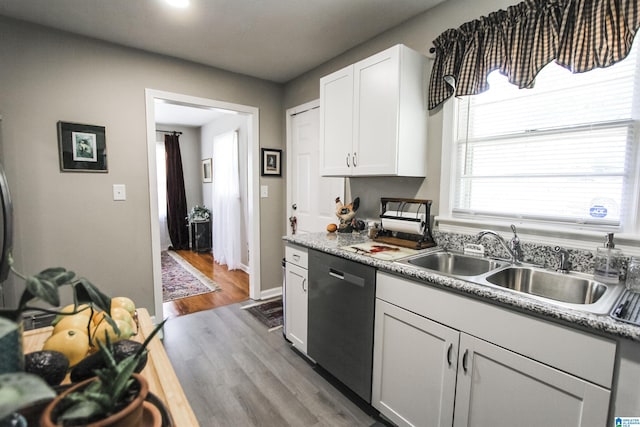 kitchen featuring dishwasher, a sink, wood finished floors, light countertops, and white cabinets