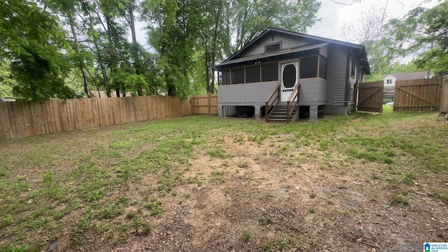 rear view of property featuring a gate and a sunroom
