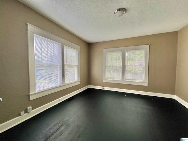 empty room featuring baseboards, a textured ceiling, and dark wood-type flooring