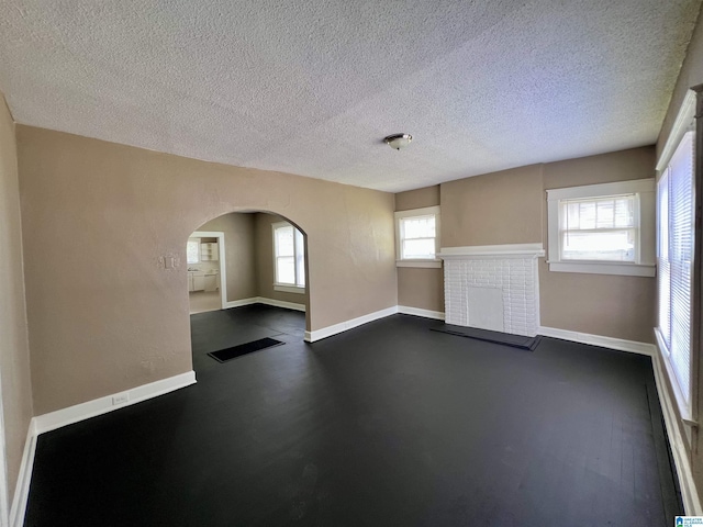 spare room with arched walkways, baseboards, and a textured ceiling