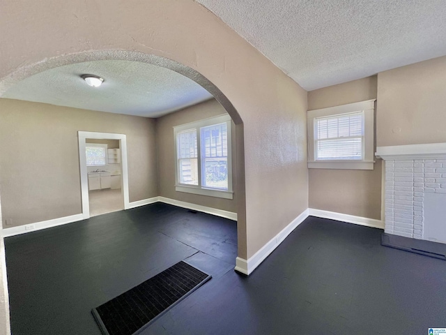 foyer with a textured ceiling, plenty of natural light, arched walkways, and baseboards