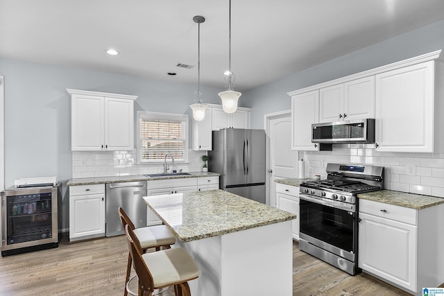 kitchen featuring appliances with stainless steel finishes, a sink, wine cooler, backsplash, and recessed lighting