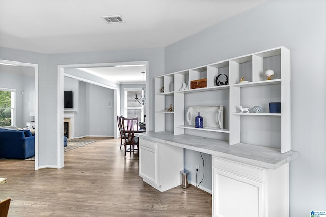 corridor featuring wood finished floors, baseboards, and a chandelier