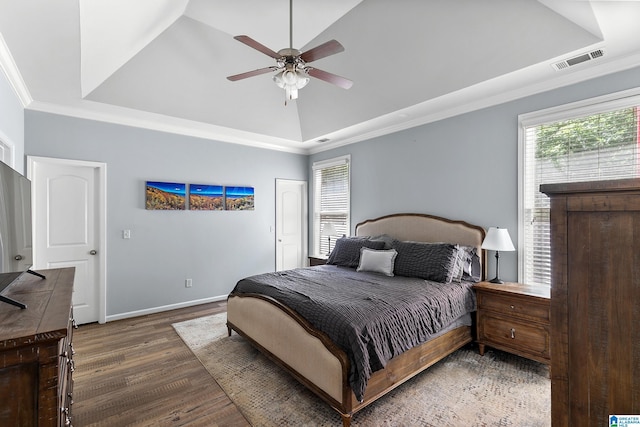 bedroom featuring a raised ceiling, wood finished floors, ornamental molding, baseboards, and a ceiling fan
