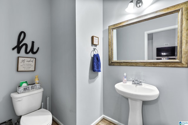 half bathroom featuring toilet and a sink