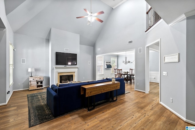living area featuring high vaulted ceiling, a ceiling fan, wood finished floors, a chandelier, and a fireplace
