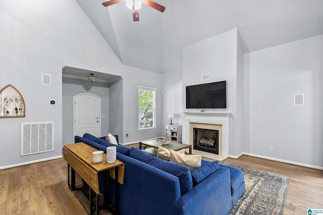 living room with high vaulted ceiling, a ceiling fan, wood finished floors, baseboards, and a fireplace with flush hearth