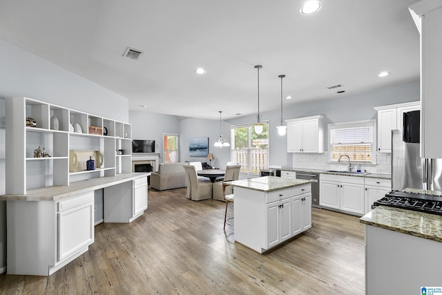 kitchen featuring appliances with stainless steel finishes, a sink, a center island, a kitchen bar, and white cabinetry