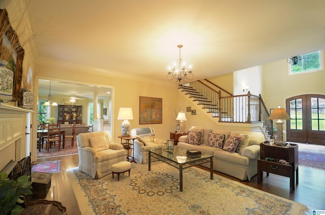 living room featuring stairway, wood finished floors, plenty of natural light, a chandelier, and crown molding