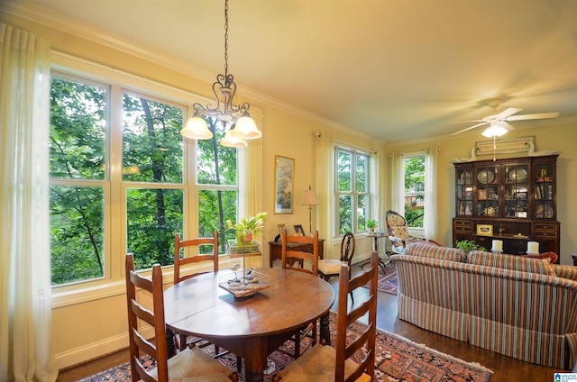 dining room with wood finished floors, ornamental molding, baseboards, a ceiling fan, and a chandelier