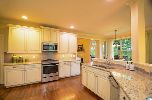 kitchen with appliances with stainless steel finishes, a sink, crown molding, backsplash, and dark wood-style floors