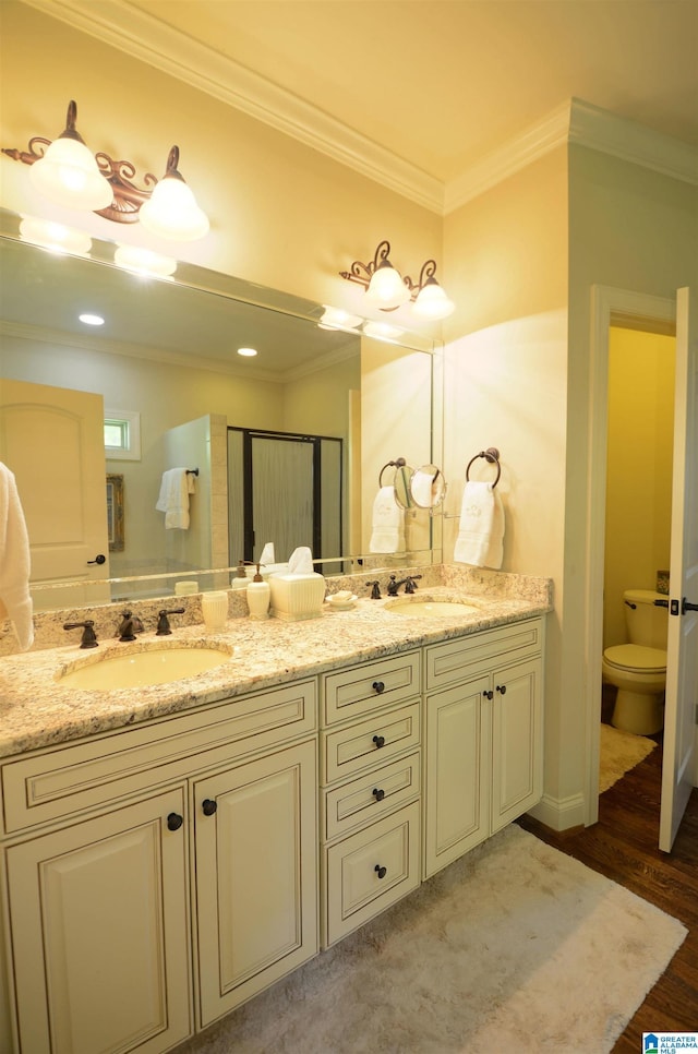 bathroom with ornamental molding, wood finished floors, double vanity, and toilet