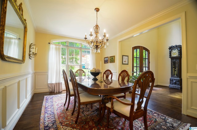 dining area with plenty of natural light, a chandelier, dark wood-style floors, ornamental molding, and wainscoting