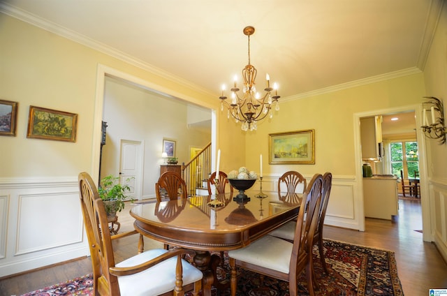 dining space with a chandelier, ornamental molding, wood finished floors, wainscoting, and stairs