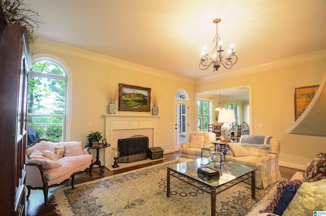 living room with a chandelier, ornamental molding, wood finished floors, healthy amount of natural light, and a fireplace with raised hearth
