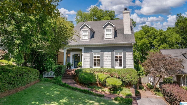cape cod house with a chimney, roof with shingles, and a front lawn