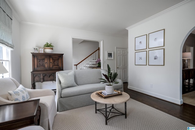 living area featuring arched walkways, dark wood-style flooring, ornamental molding, stairway, and baseboards