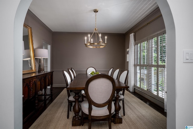 dining space with arched walkways, a chandelier, wood finished floors, and ornamental molding