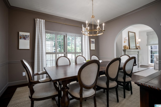 dining area with arched walkways, a chandelier, healthy amount of natural light, crown molding, and wood finished floors