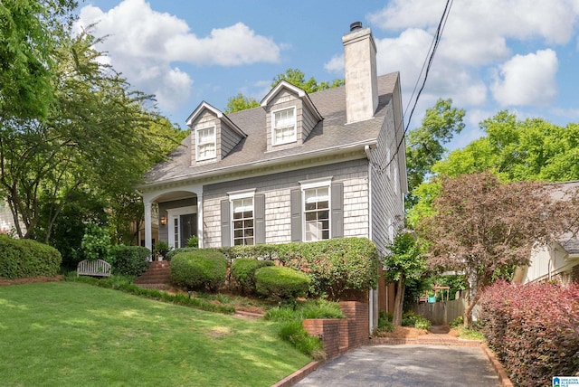 new england style home with a chimney and a shingled roof