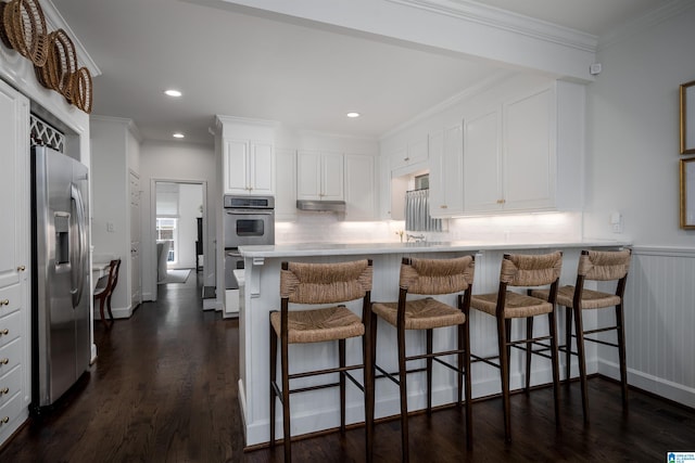 kitchen with appliances with stainless steel finishes, white cabinets, dark wood-style flooring, light countertops, and tasteful backsplash