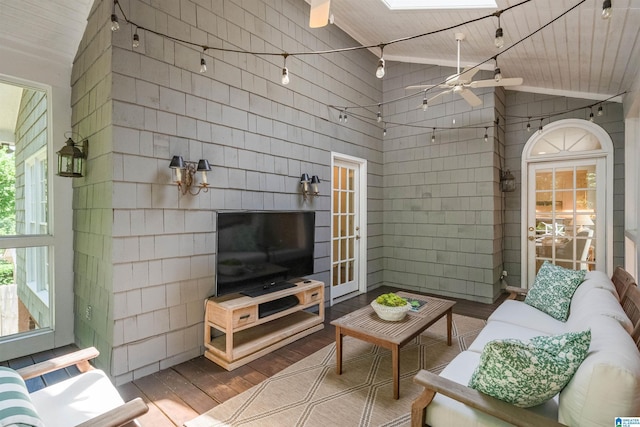 living area with wood finished floors, healthy amount of natural light, a ceiling fan, a skylight, and wooden ceiling