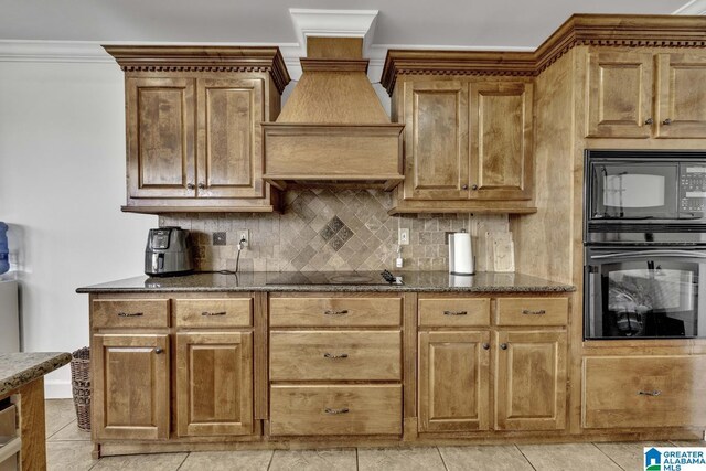 kitchen featuring black appliances, tasteful backsplash, dark stone counters, premium range hood, and brown cabinetry