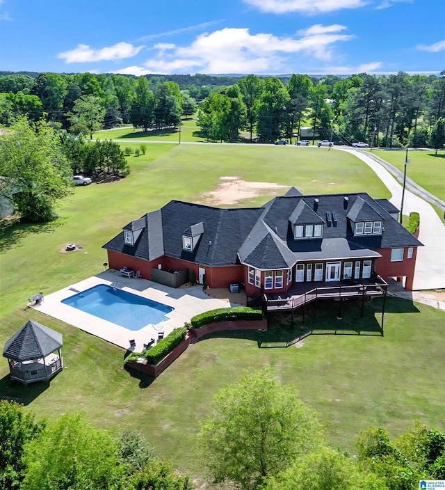 aerial view of property and surrounding area with a pool and a tree filled landscape
