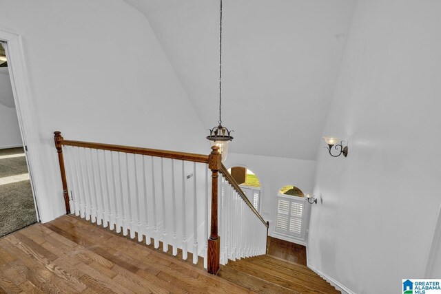 stairway with wood finished floors and vaulted ceiling