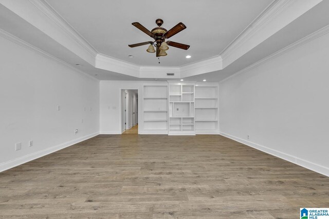 unfurnished bedroom featuring a raised ceiling, crown molding, wood finished floors, baseboards, and recessed lighting
