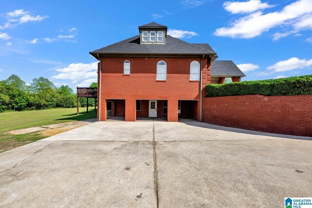 view of home's exterior with brick siding, a lawn, and driveway