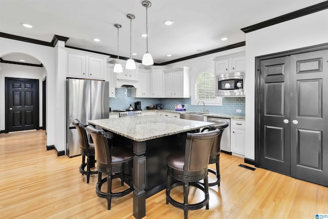 4017 Milner Way, Birmingham, AL 35242 - kitchen featuring appliances with stainless steel finishes, crown molding, a kitchen island, light wood finished floors, and white cabinetry