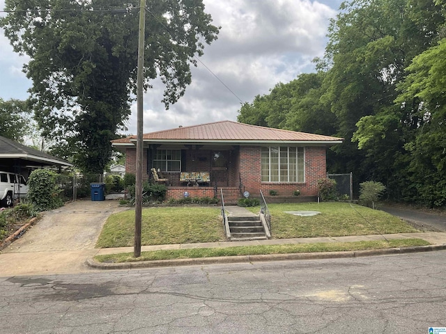 view of front of house featuring a porch, brick siding, a front lawn, concrete driveway, and metal roof