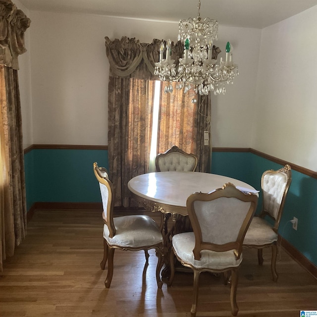 dining room featuring a chandelier, wood finished floors, and baseboards