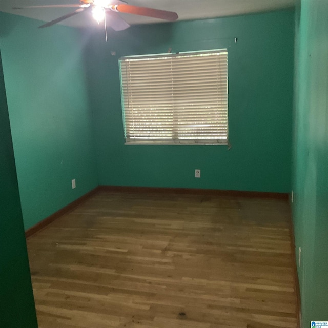 spare room featuring wood finished floors, ceiling fan, and baseboards