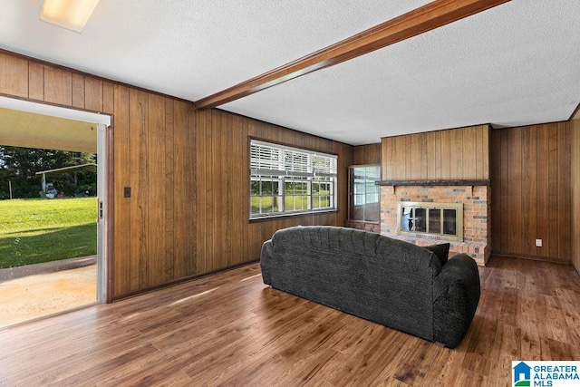 5241 County Road 48, Jemison, AL 35085 - living room featuring wood finished floors, wooden walls, a textured ceiling, beam ceiling, and a fireplace